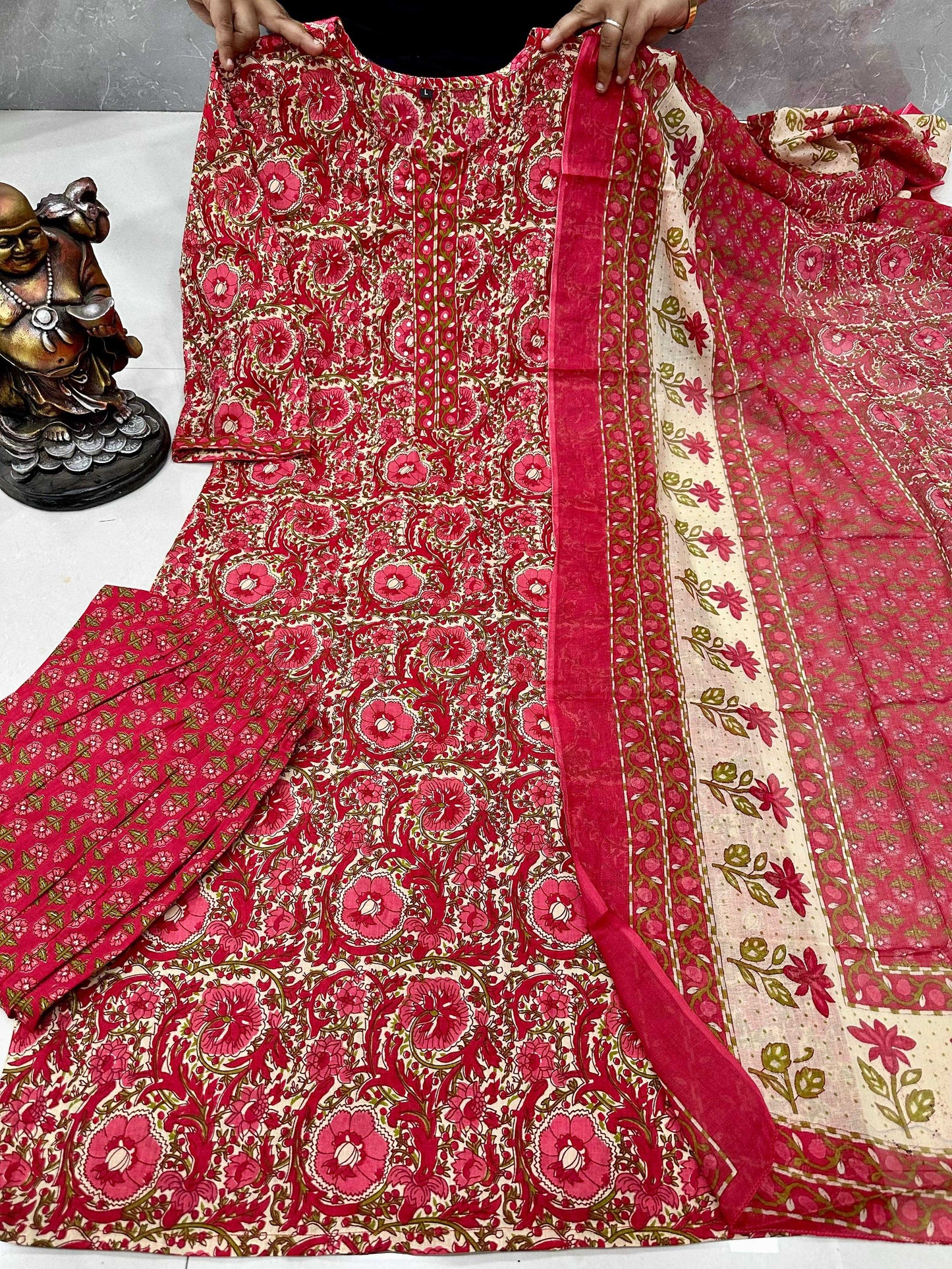 Red and pink embroidered fabric with intricate patterns on a white surface.