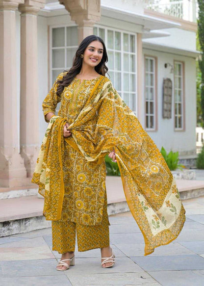 Woman in a yellow patterned outfit standing in front of a building.