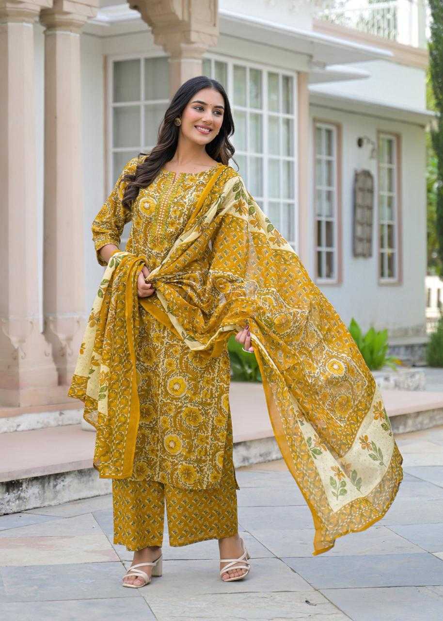 Woman in a yellow patterned outfit standing in front of a building.