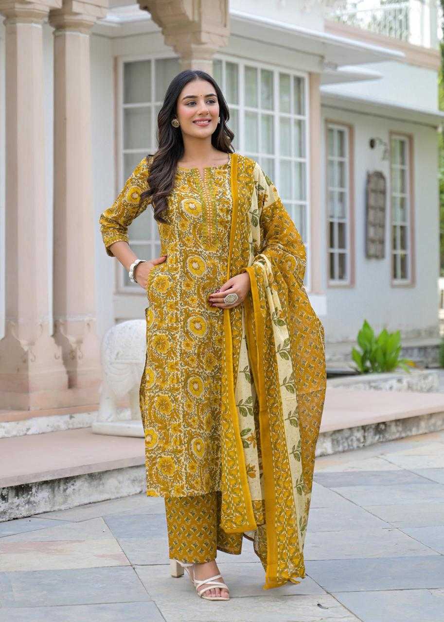 Woman in a yellow traditional outfit standing in front of a building.