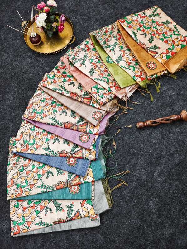 A fan arrangement of multiple folded patterned fabric scarves or shawls on a dark textured surface, with a small decorative tray of flowers and a wooden object nearby as styling props.