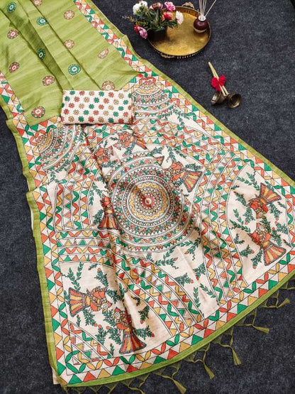 A traditional Indian saree displayed flat on a dark textured surface, featuring a light olive green border, a cream-colored body with intricate multicolor mandala and floral prints, and a matching small blouse piece.