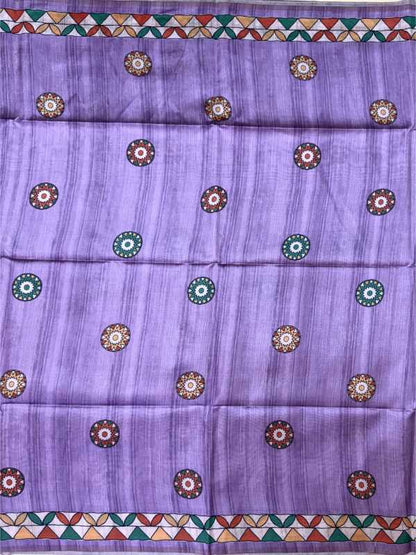 A lavender purple fabric, likely a saree, featuring a subtle vertical texture and a repeating pattern of circular floral motifs in brown, green, and white. The fabric is finished with decorative borders at the top and bottom containing a geometric triangle pattern in green, orange, and white.