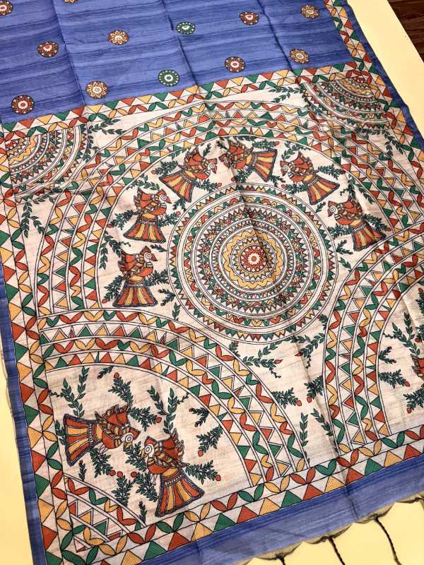 A square cotton fabric piece, likely a sari or large scarf, featuring a traditional Indian hand-painted style folk art design. The design has a blue border with small floral motifs, a central cream-colored field with colorful circular mandalas and dancing figures, and a geometric border in green, orange, and red.