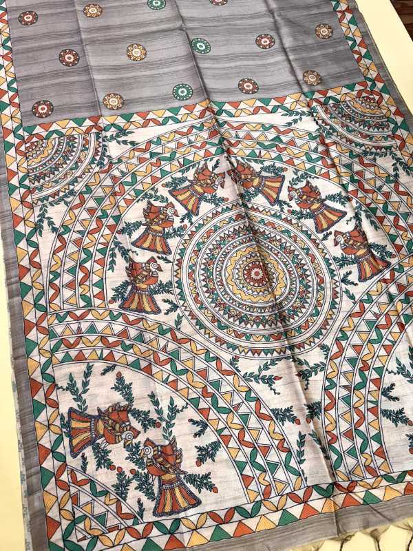 A folded and draped piece of traditional Indian block-printed fabric, likely a saree or dupatta, featuring a complex mandala and floral pattern in orange, green, red, and blue on a light gray base.