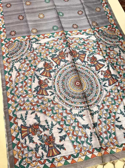 A folded and draped piece of traditional Indian block-printed fabric, likely a saree or dupatta, featuring a complex mandala and floral pattern in orange, green, red, and blue on a light gray base.