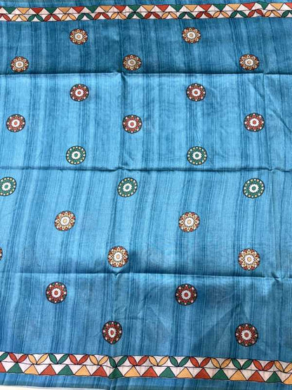 A blue fabric panel or scarf featuring a vertical textured stripe pattern and repeated circular floral motifs in red, green, and cream, with geometric borders at the top and bottom.