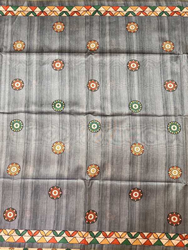 A gray striped fabric, likely a saree or scarf, decorated with small circular floral motifs in orange, green, and cream, featuring a geometric pattern border at the top and bottom.