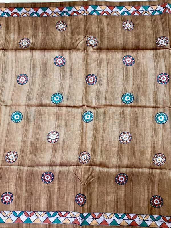 A brown woven fabric, likely a saree or scarf, featuring a vertical striped texture and a repeating pattern of colorful circular medallions. The fabric is finished with geometric borders at the top and bottom in red, blue, green, and white.