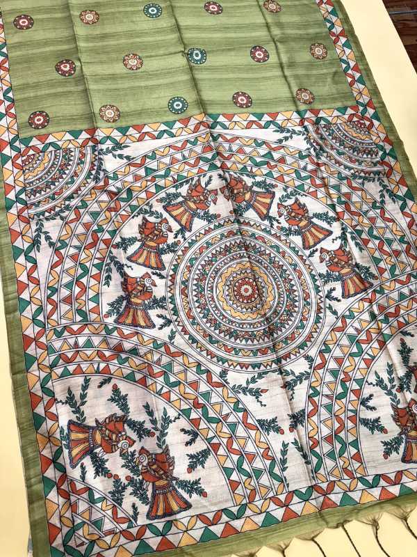 A hand-painted Indian textile, likely a saree or scarf, featuring a sage green border and a white central field decorated with intricate multicolor folk art motifs, including mandalas and figures.