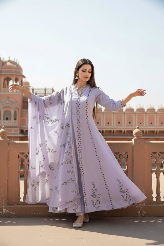 Woman in a white embroidered outfit standing in front of a historic building with a clear sky.