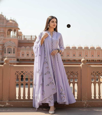 Woman in a light purple traditional outfit standing in front of a historic building.