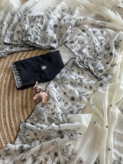 Black clutch bag with floral design on a white fabric background