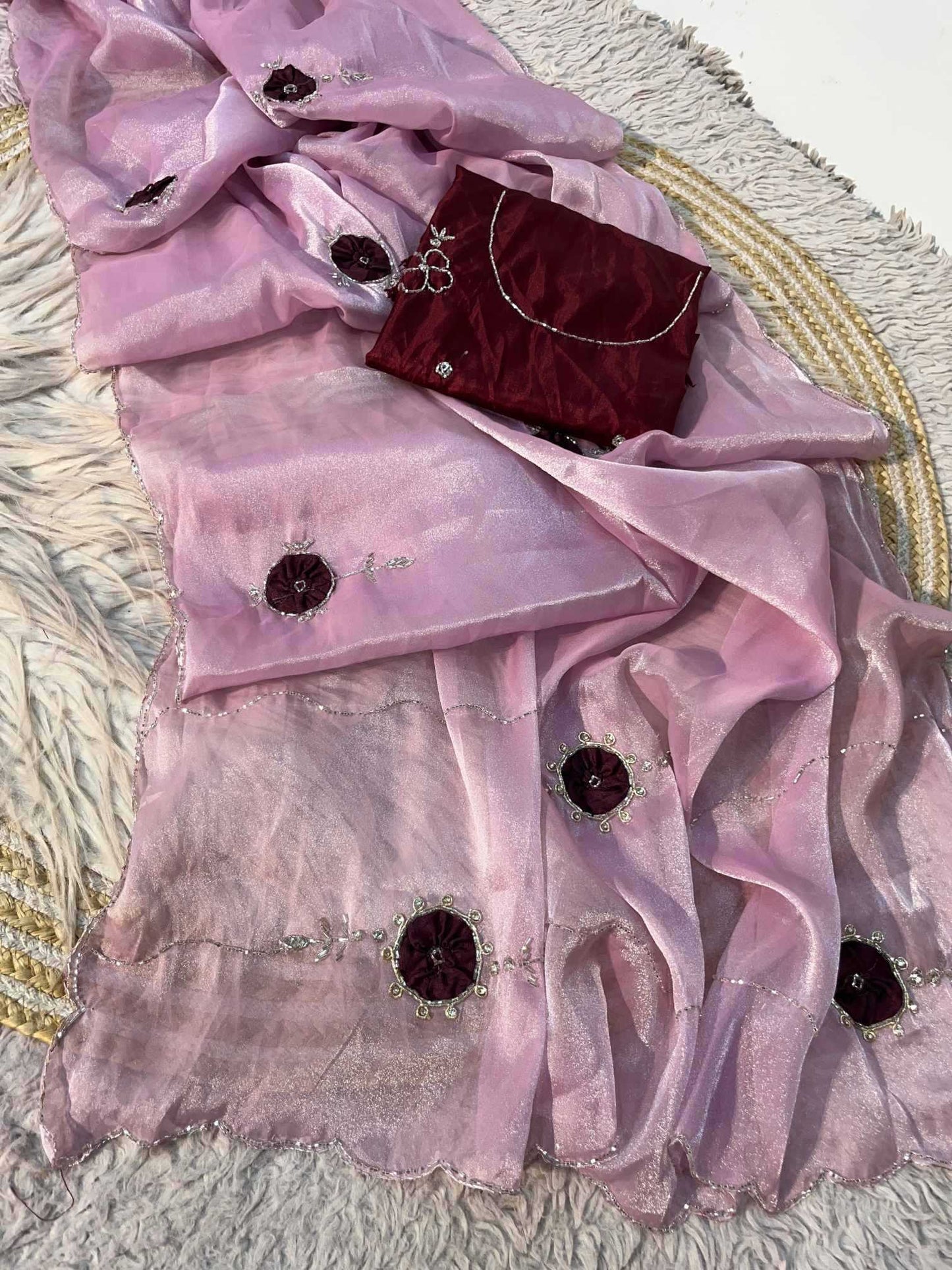 A light pink sheer organza dupatta with dark maroon embroidered floral motifs and silver mirror work, displayed alongside a matching dark maroon velvet clutch purse on a textured white rug.
