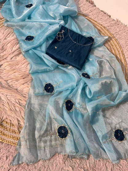 A light blue sheer dupatta with dark blue floral motifs and silver embroidery, draped over a dark blue fabric piece on a pink textured rug.
