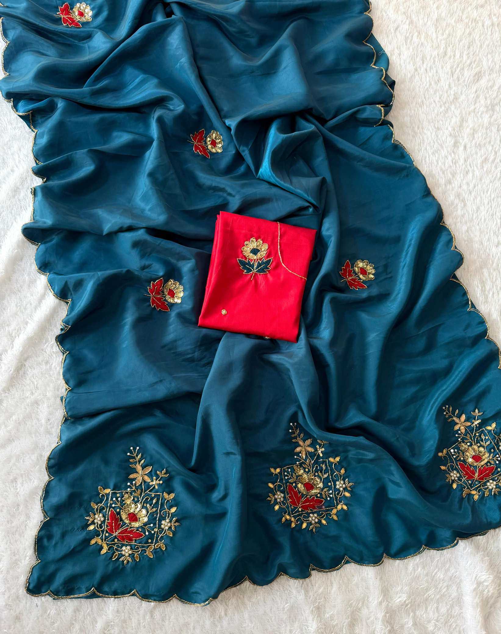 Blue saree with floral embroidery and a red box on a textured white background
