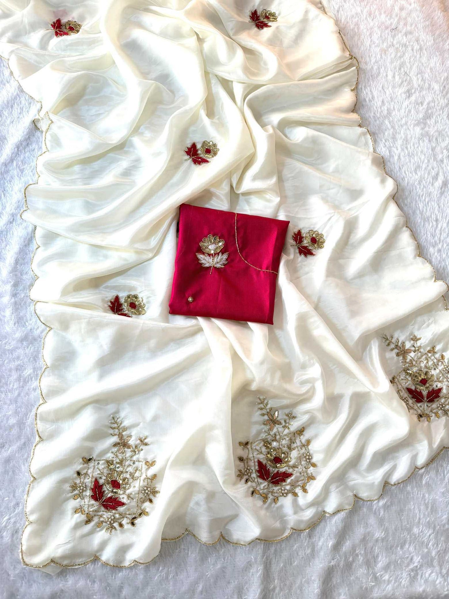 An ivory white silk saree drape with gold and red floral embroidery, featuring a matching red silk pocket square with a gold embroidered motif.