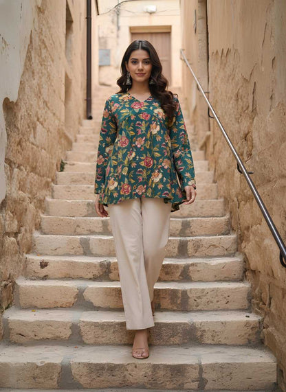 Woman in a floral top and beige pants standing on stone steps in an alleyway.