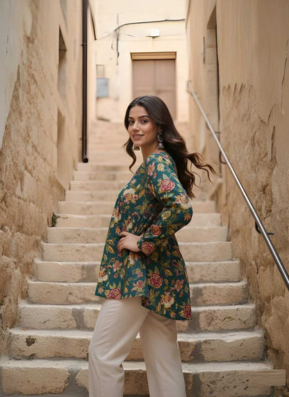 Woman in a floral top and white pants standing on stone steps in an alleyway.