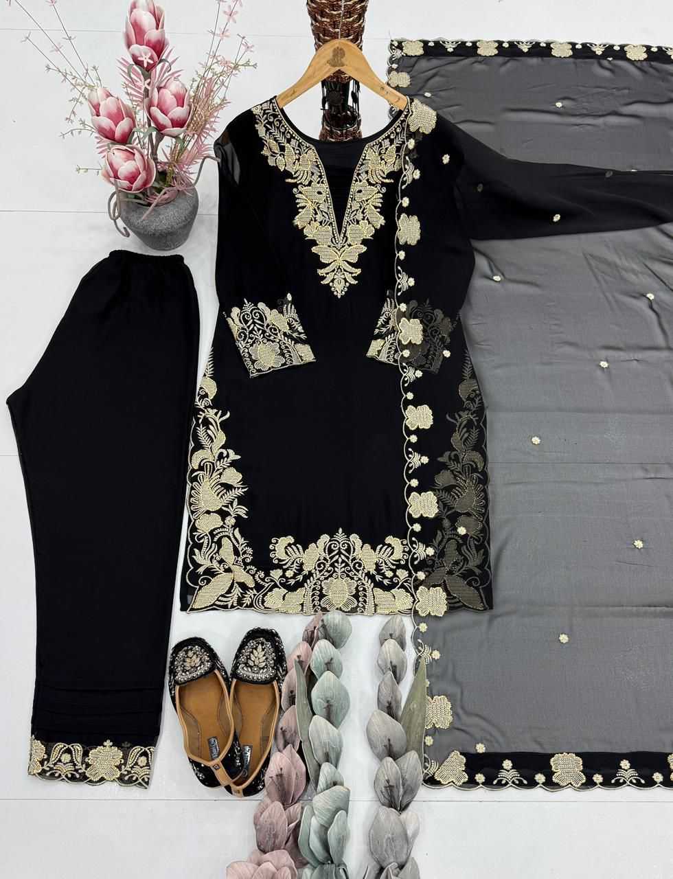Black outfit with gold embroidery on a hanger, accompanied by shoes and decorative items.