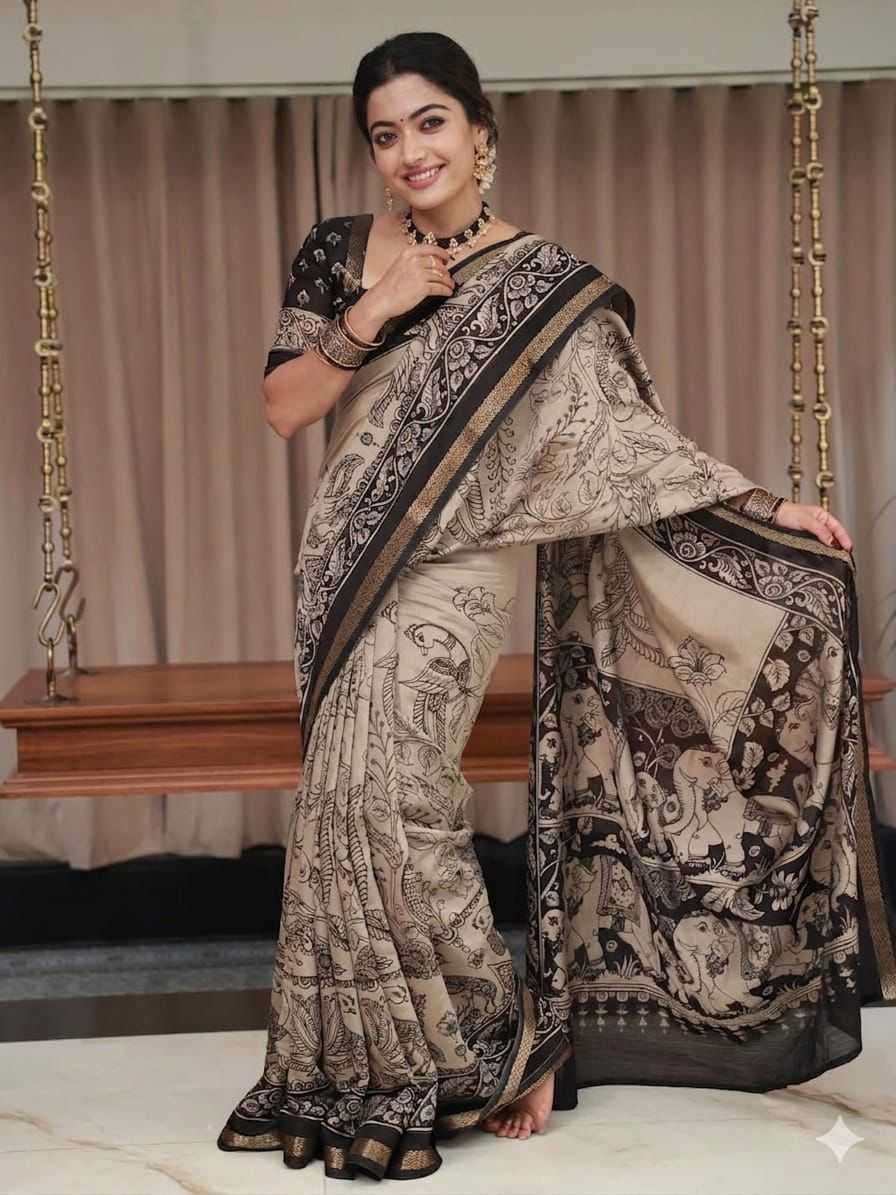Woman wearing a traditional saree with intricate patterns in a room setting.