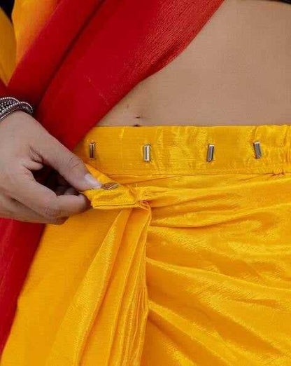 Close-up of a person adjusting a yellow garment with red fabric in the background