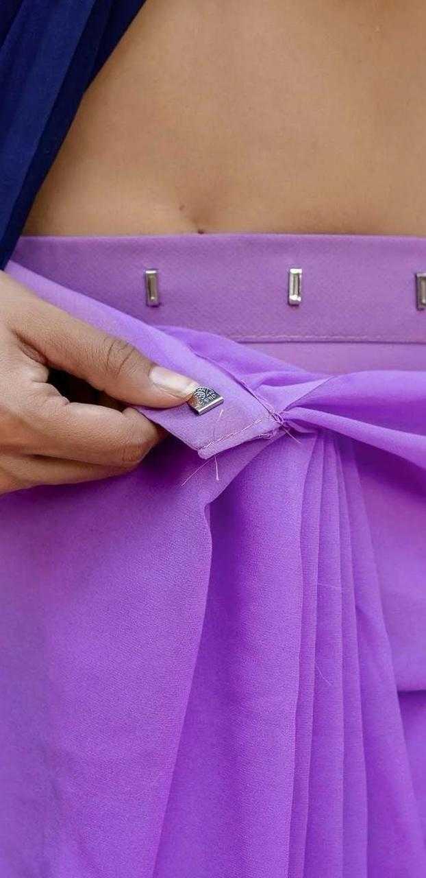Close-up of a person adjusting a purple garment with metallic buttons.
