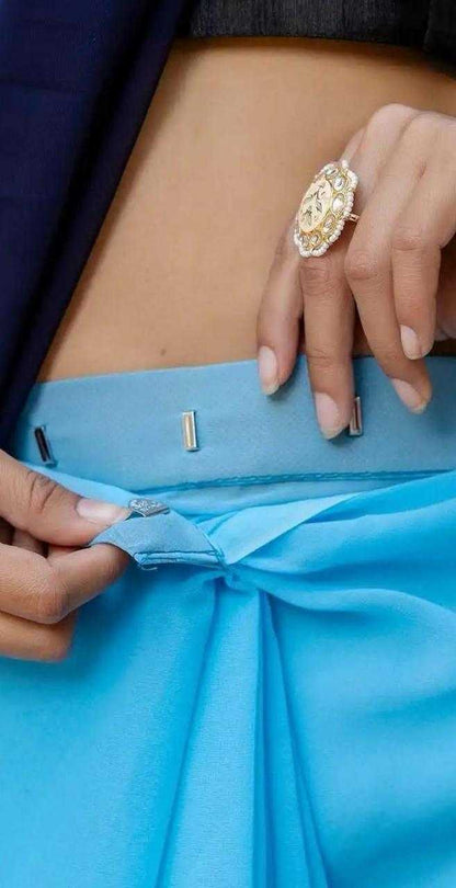 Close-up of a person adjusting a blue garment with a gold ring on a dark background
