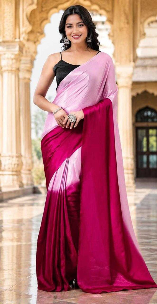 Woman wearing a pink and red saree in front of an architectural background