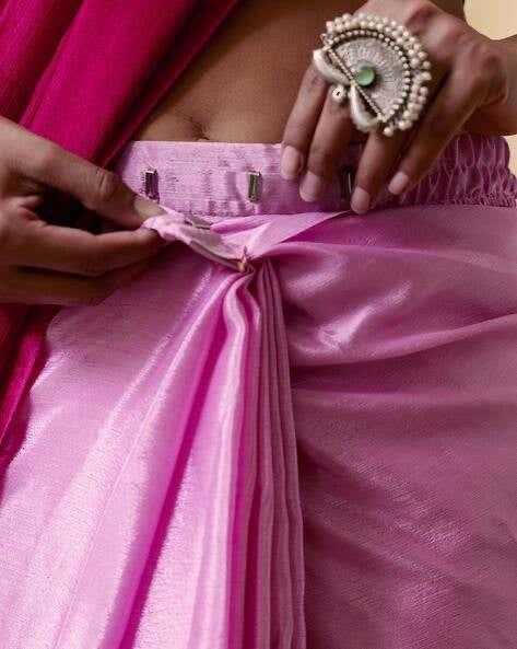 Close-up of a person adjusting a pink garment with a decorative ring on a blurred background