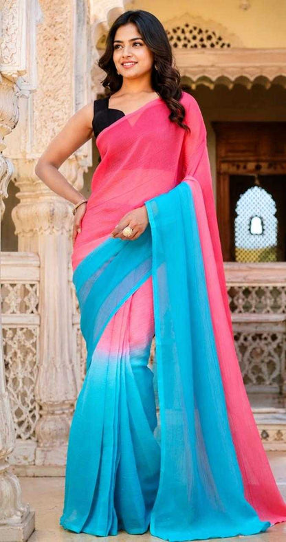 Woman wearing a pink and blue saree in front of an architectural background