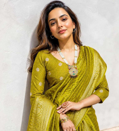 Woman wearing a green saree with jewelry against a white background