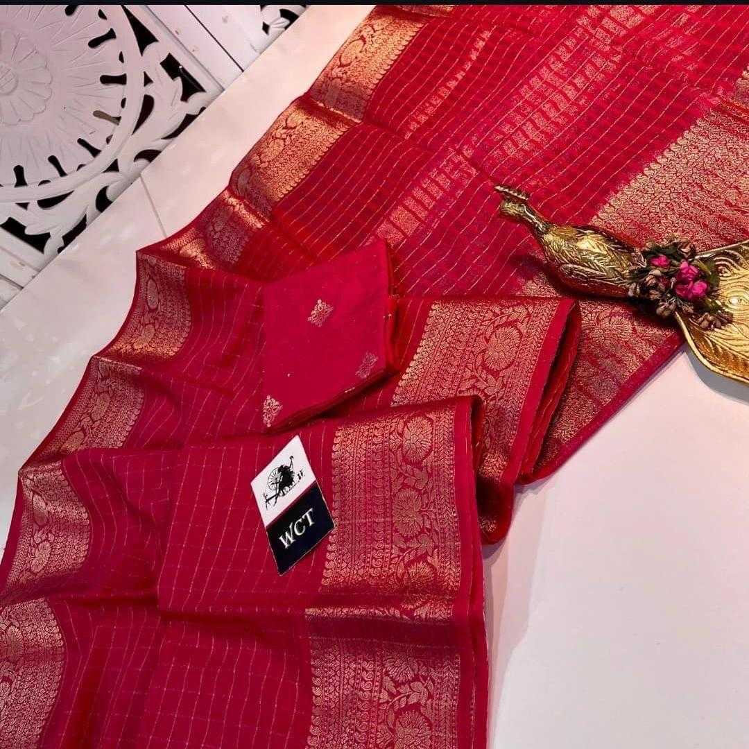Red saree with gold patterns on a white surface, featuring a visible brand label.