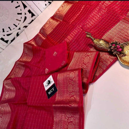 Red saree with gold patterns on a white surface, featuring a visible brand label.