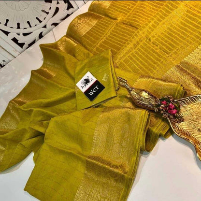 Gold saree with a decorative brooch on a white surface, featuring the WCT brand.