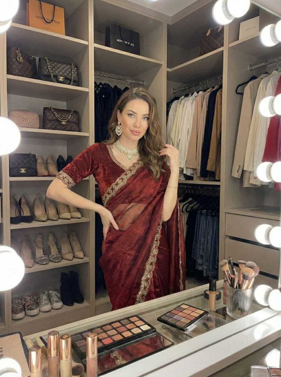 Woman in a red saree standing in a well-lit wardrobe with shelves of shoes and bags.