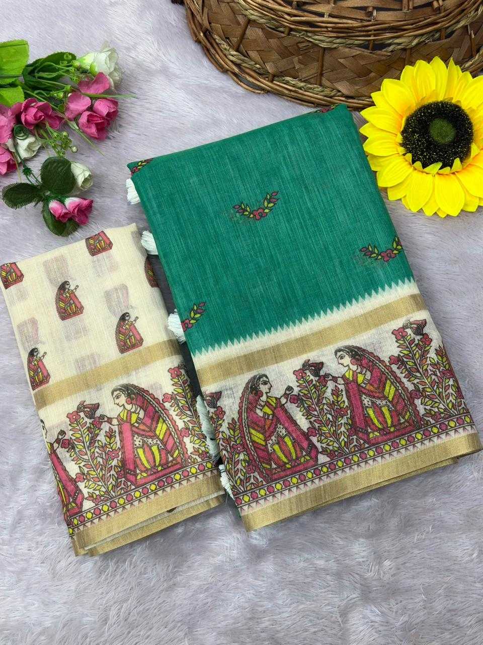A folded green and beige cotton saree with traditional Indian block-print patterns, displayed on a gray faux fur surface with decorative flowers and a wicker basket.