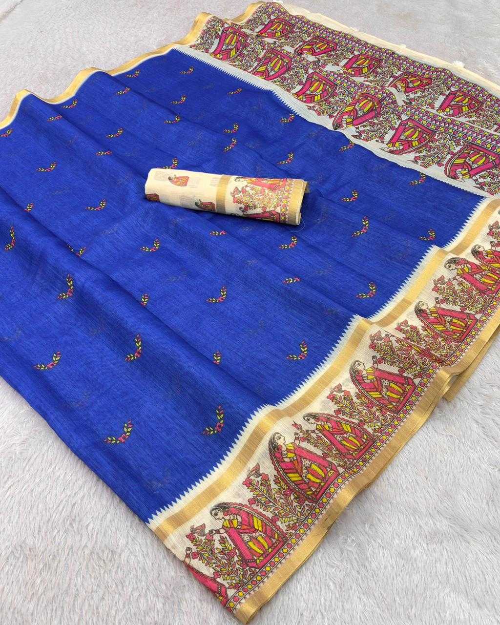 A royal blue saree fabric with small gold motifs and a wide beige border featuring red and gold traditional patterns, laid flat on a white textured surface with a matching rolled fabric piece placed on top.