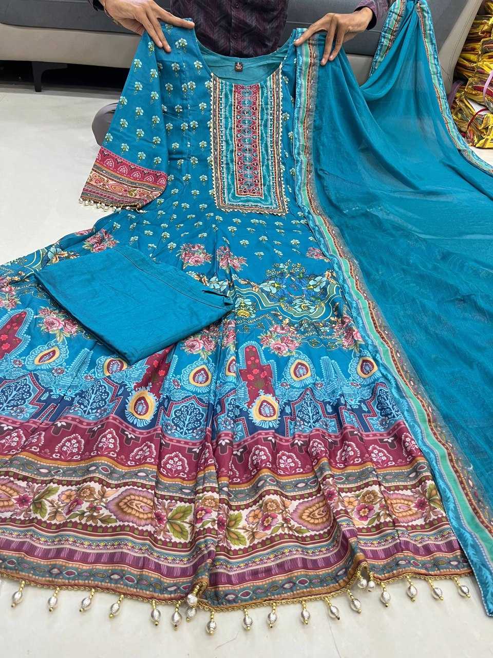 Colorful traditional outfit with a blue dupatta on a white floor.
