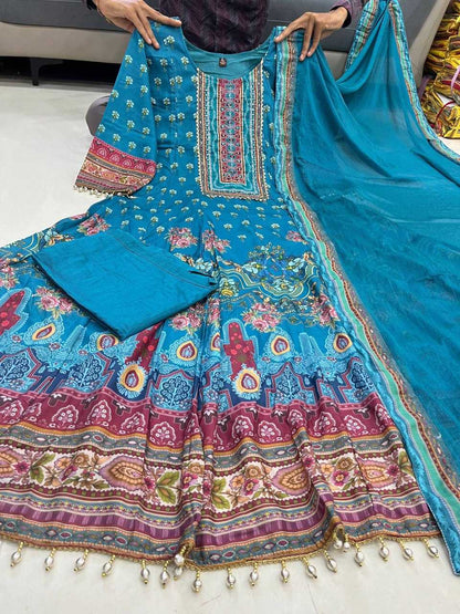 Colorful traditional outfit with a blue dupatta on a white floor.