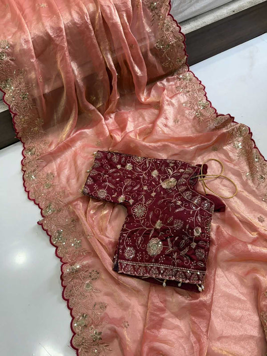 Pink saree with gold border and red embroidered blouse on a white surface