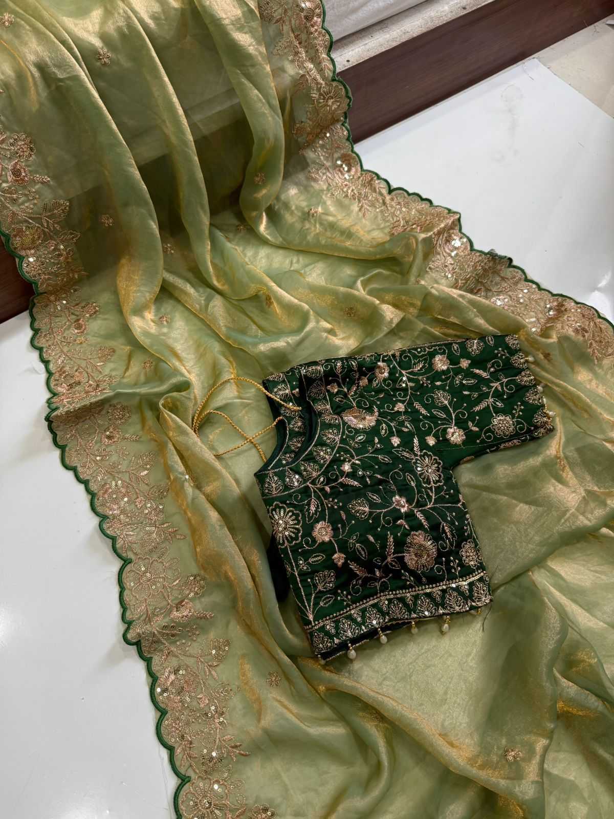 Green embroidered blouse with matching fabric on a white surface