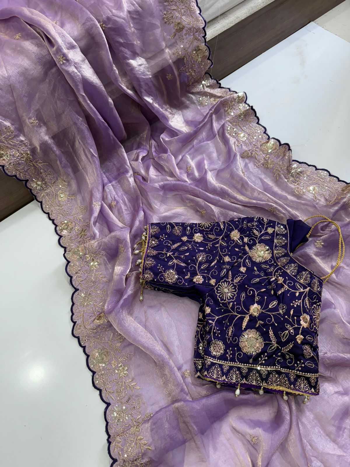 Purple saree with gold embroidery on a white surface