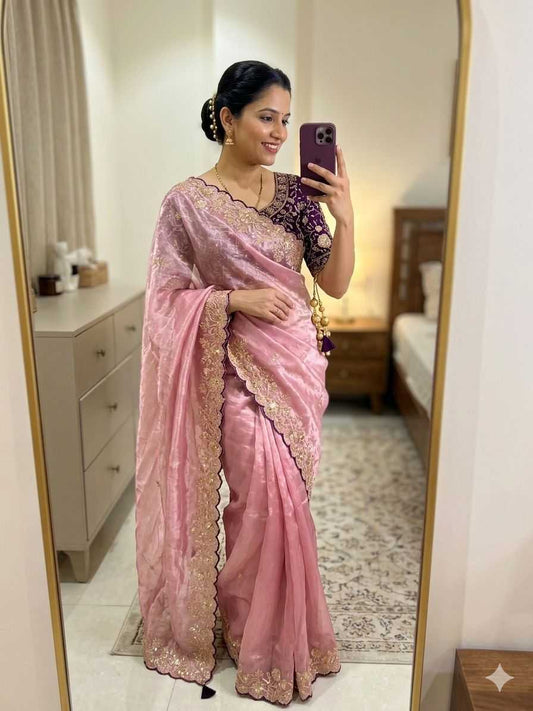 Woman in a pink saree taking a mirror selfie in a room.