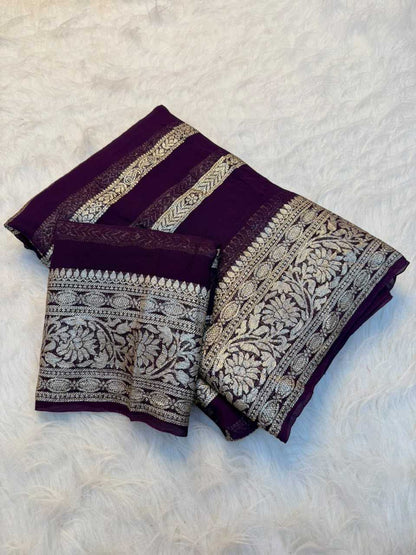 A folded dark purple fabric piece with ornate silver-toned floral and geometric woven borders, displayed on a white faux-fur surface.