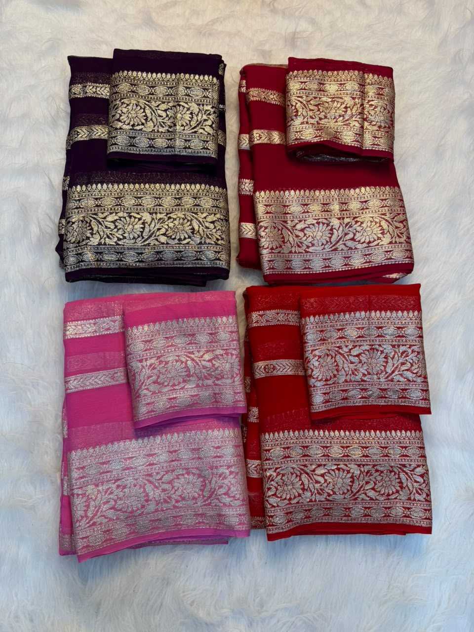 Four folded sarees with ornate zari borders arranged in a 2x2 grid on a white faux fur background. The sarees are in dark purple, red, and pink, each with a matching dupatta.