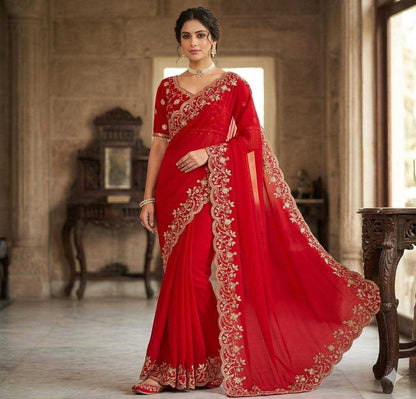 Woman wearing a red saree with gold embroidery in an elegant room.