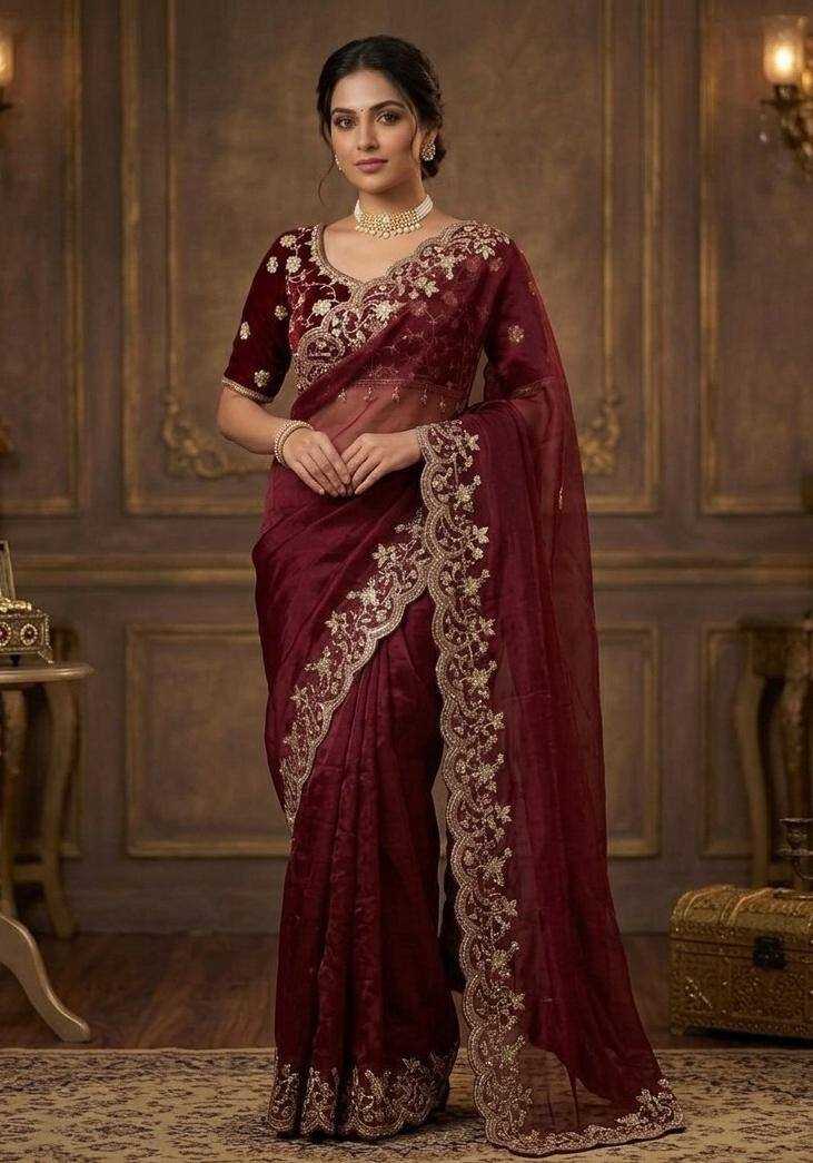 Woman wearing a maroon saree with gold embroidery in an elegant room.