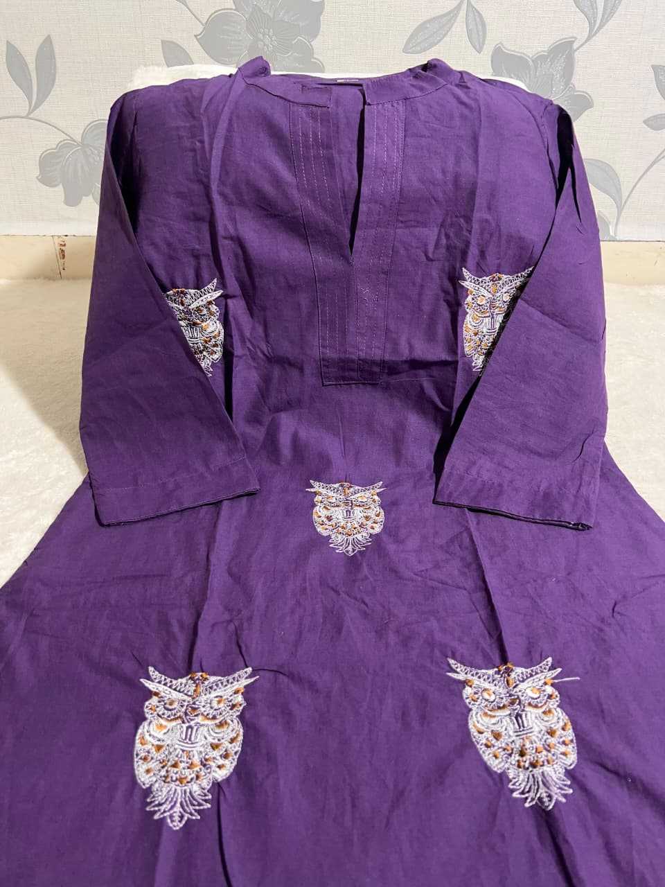 Purple dress with decorative owl patterns on a neutral background