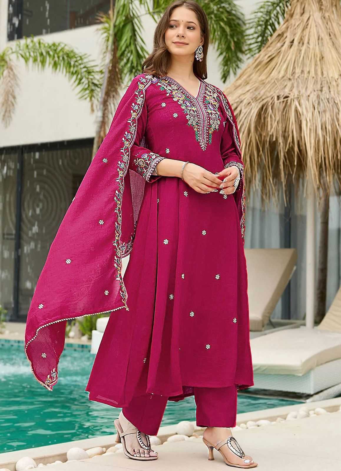 Woman in a pink traditional outfit with embroidery standing by a poolside.